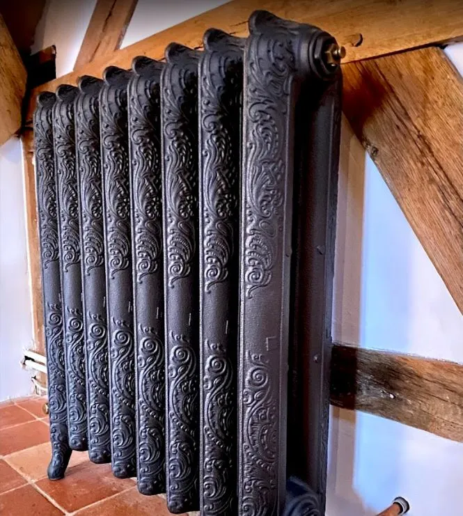 Radiateur orné placé devant une structure à colombages