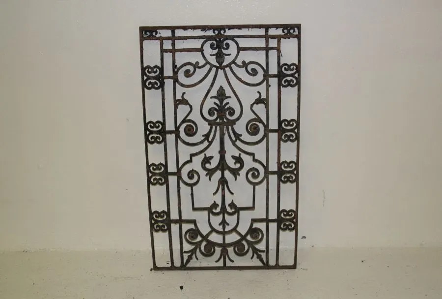 Grille ancienne en fonte à volutes et motif central