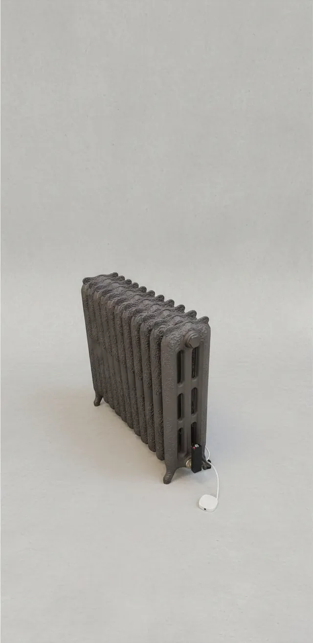 Radiateur en fonte ornementé vu de trois quarts avec son équipement électrique